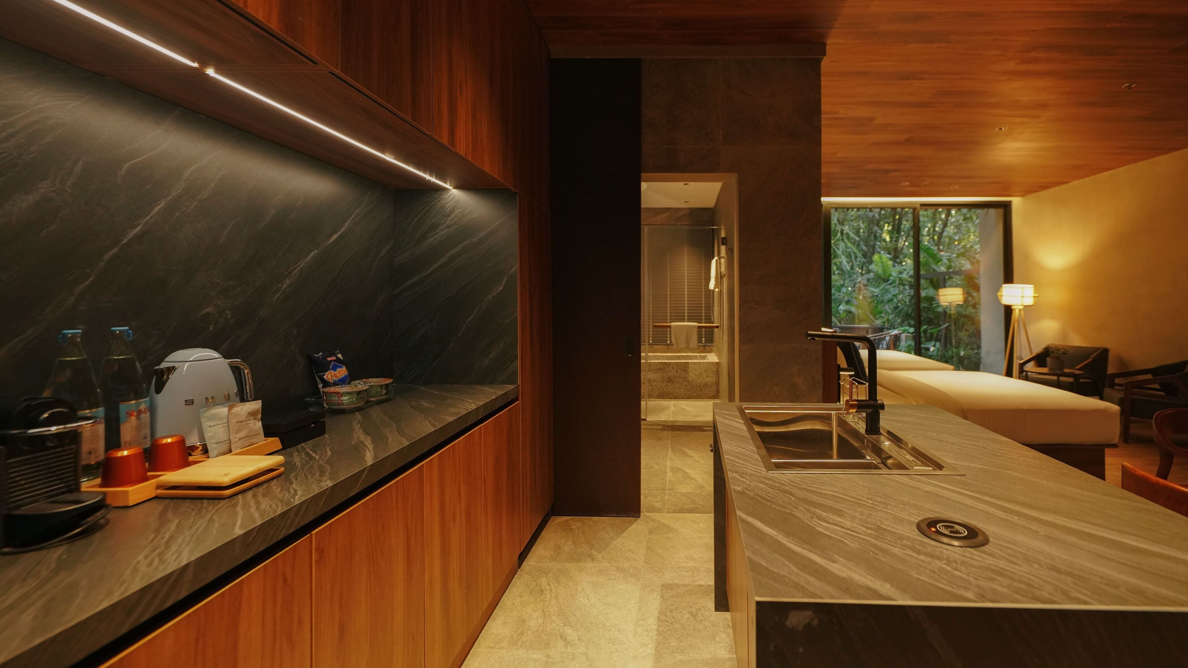 A modern kitchen with a marble countertop, wooden cabinets, and a view of the outdoors.