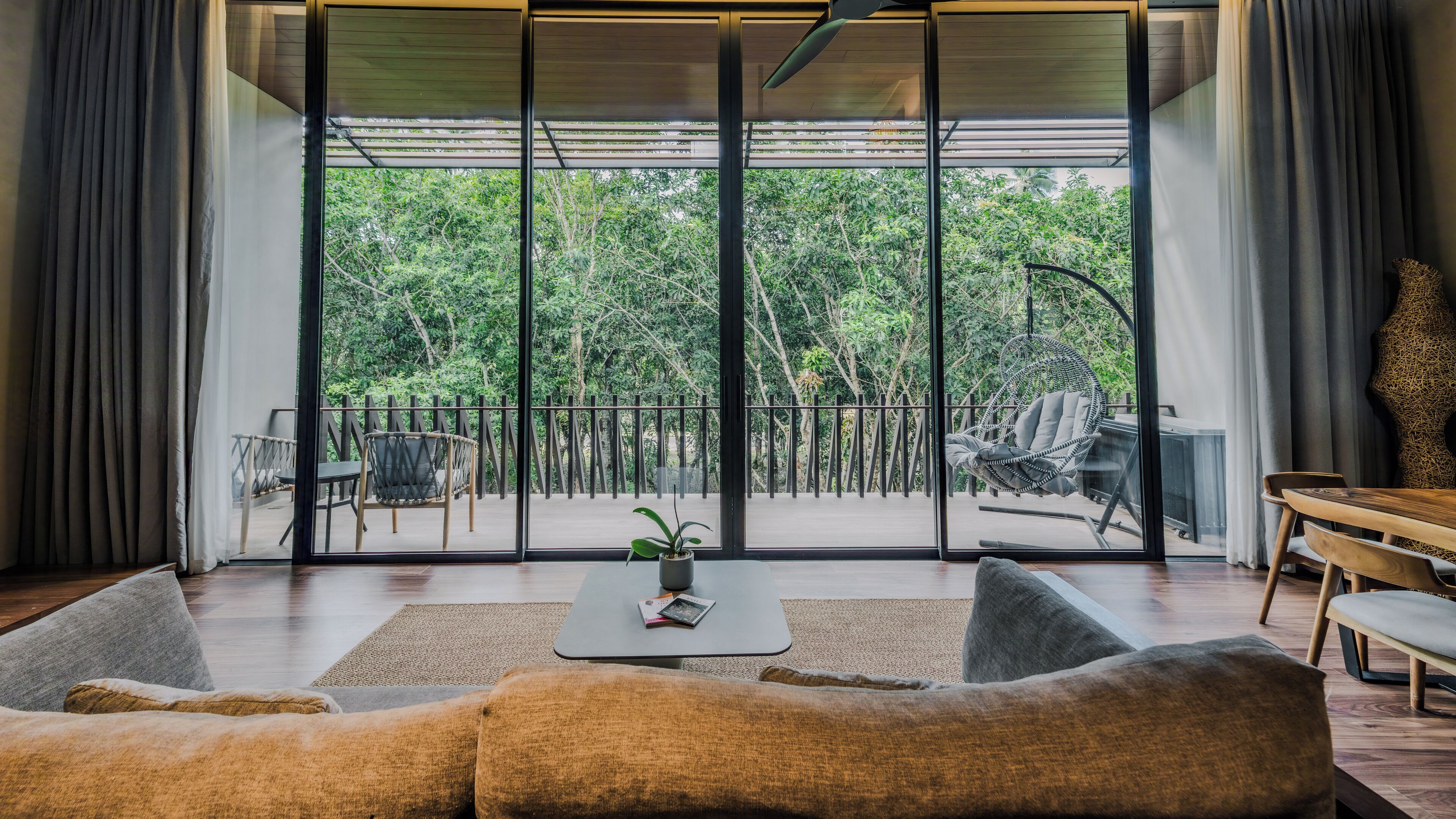 A modern living room with a large sliding glass door leading to a balcony with outdoor furniture.