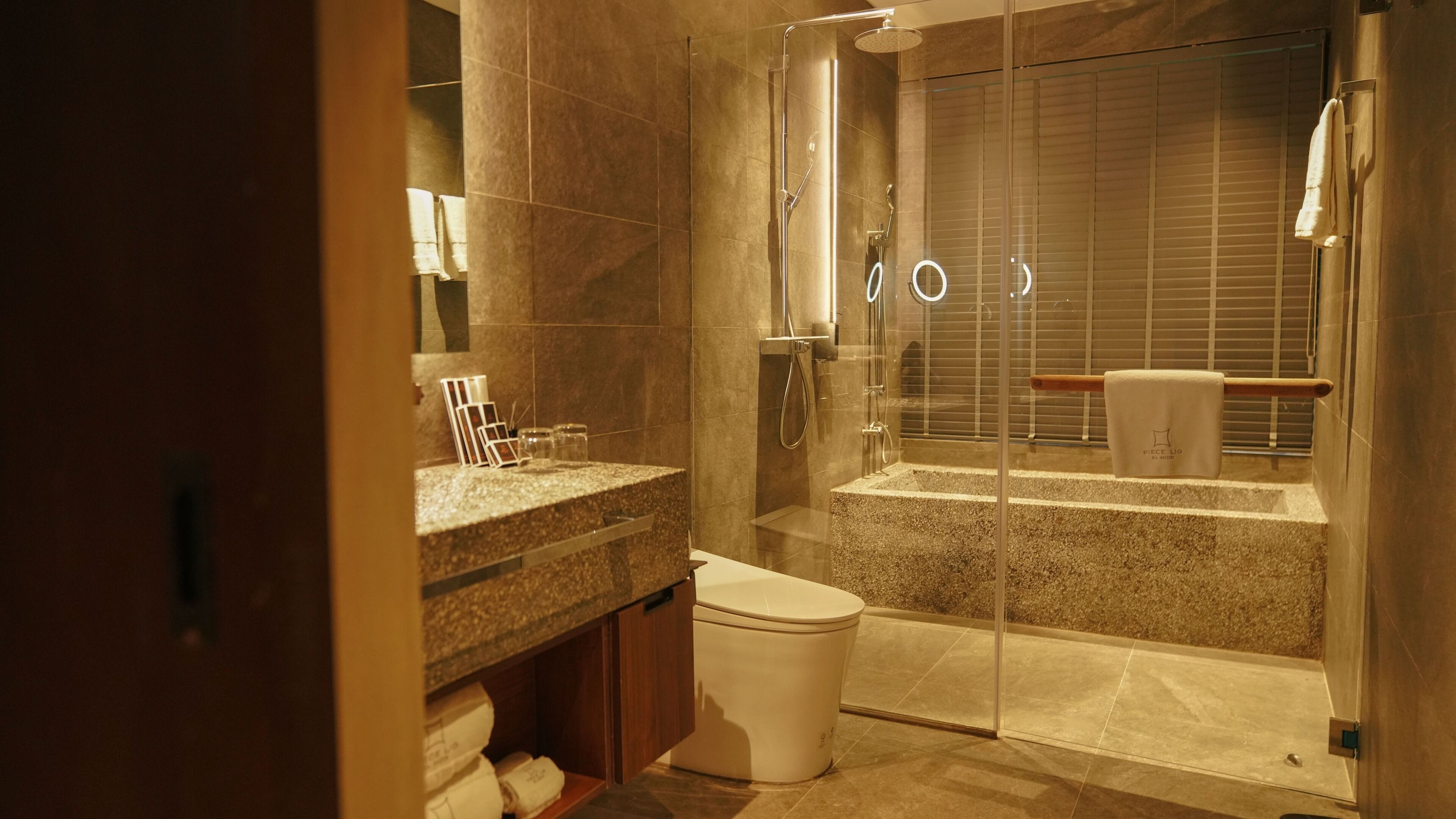 Un baño moderno con ducha de vidrio, tocador con encimera de mármol y un inodoro.