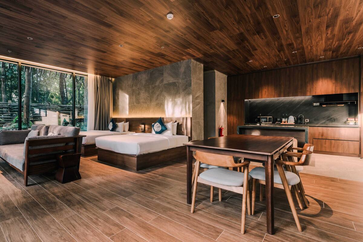 Een moderne hotelkamer met een houten plafond, een groot bed, een eettafel en een kitchenette.