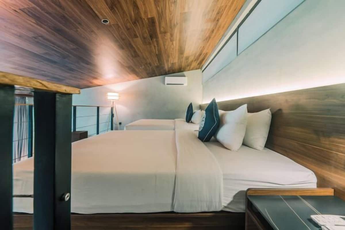 Een moderne slaapkamer met een groot bed, een nachtkastje en een houten plafond.