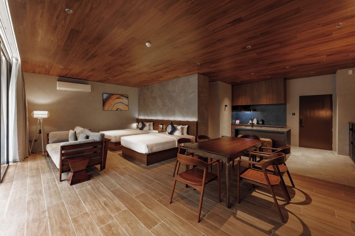 Een moderne hotelkamer met een houten plafond, een zithoek, een kitchenette en een groot bed.