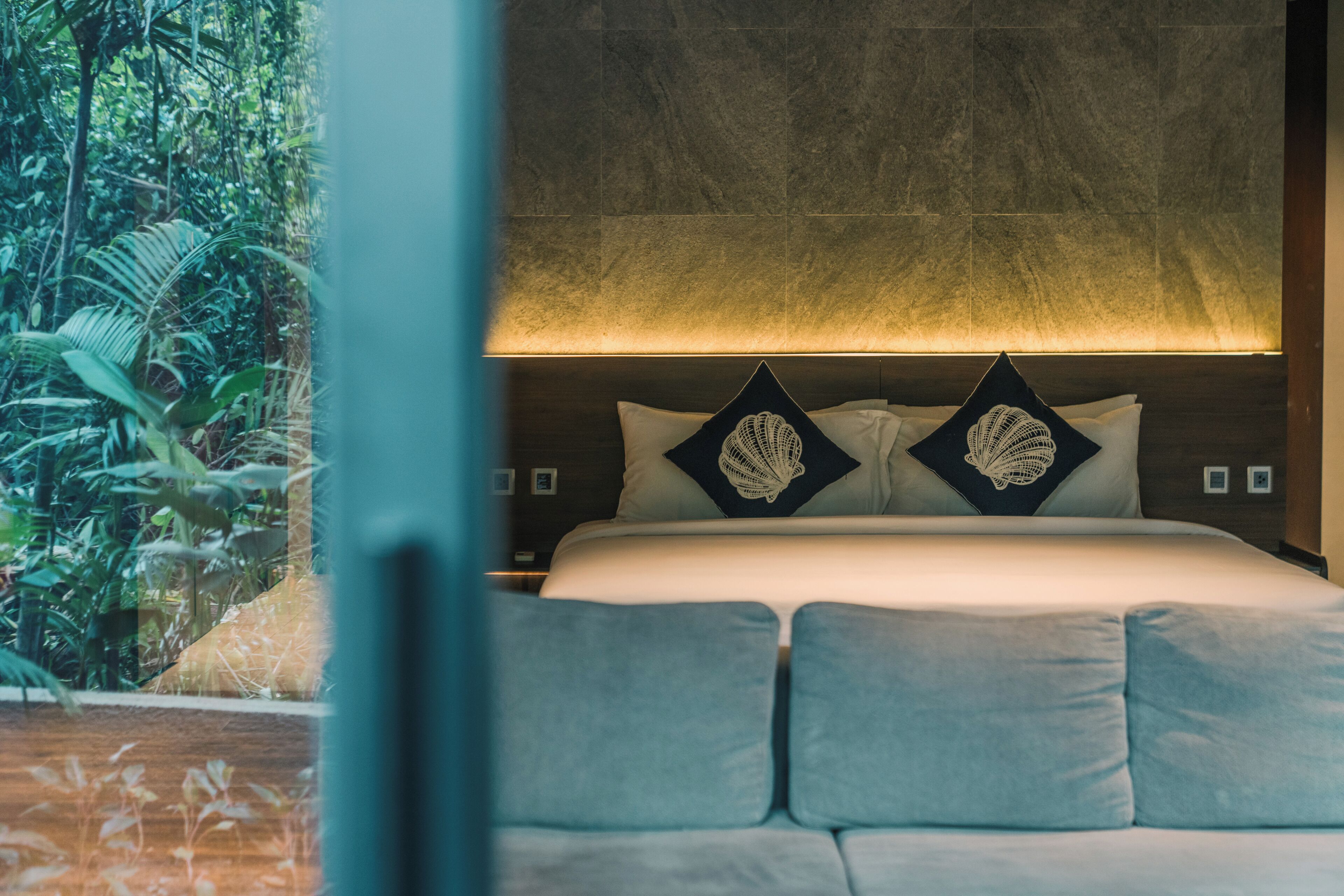 Un dormitorio con cama, almohadas y vistas al verdor.