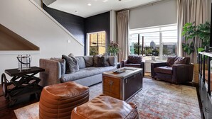 Ein modernes Wohnzimmer mit einer Couch, einem Hocker und einem Vintage-Koffer.