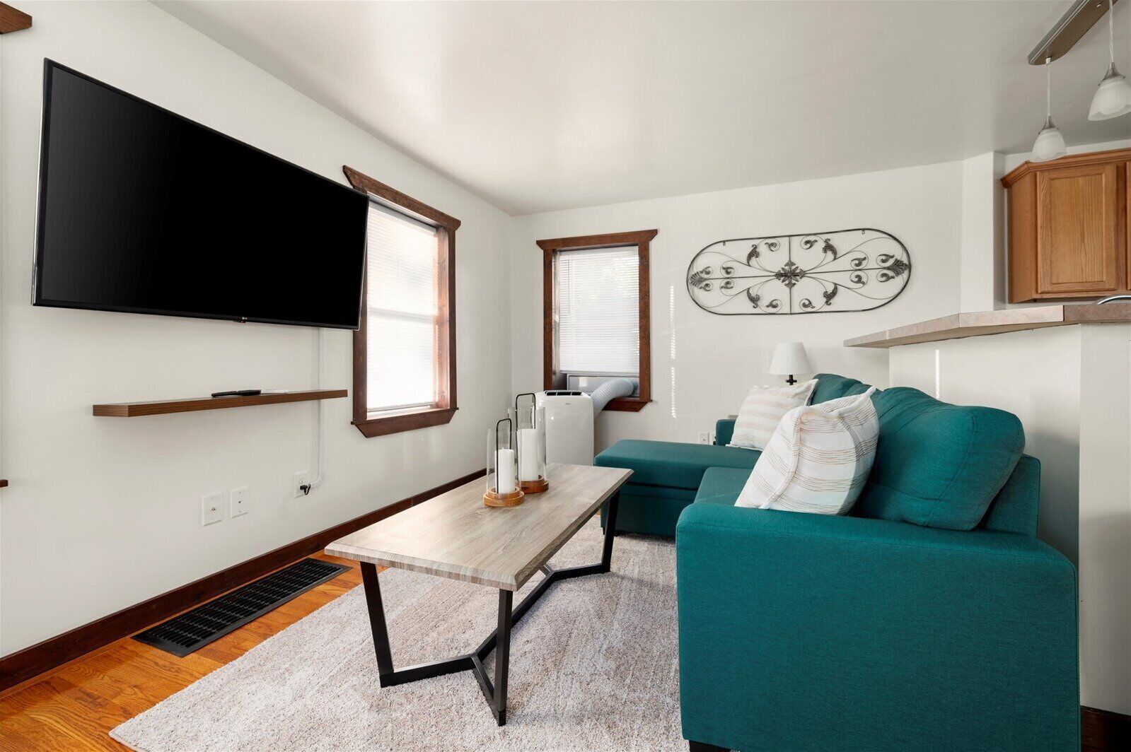 Una sala de estar moderna con un televisor de pantalla plana, un sofá color turquesa y un adorno de pared.