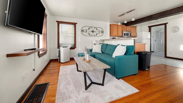 Un salon moderne avec un canapé de couleur turquoise, une table basse en bois et un téléviseur à écran plat fixé au mur.