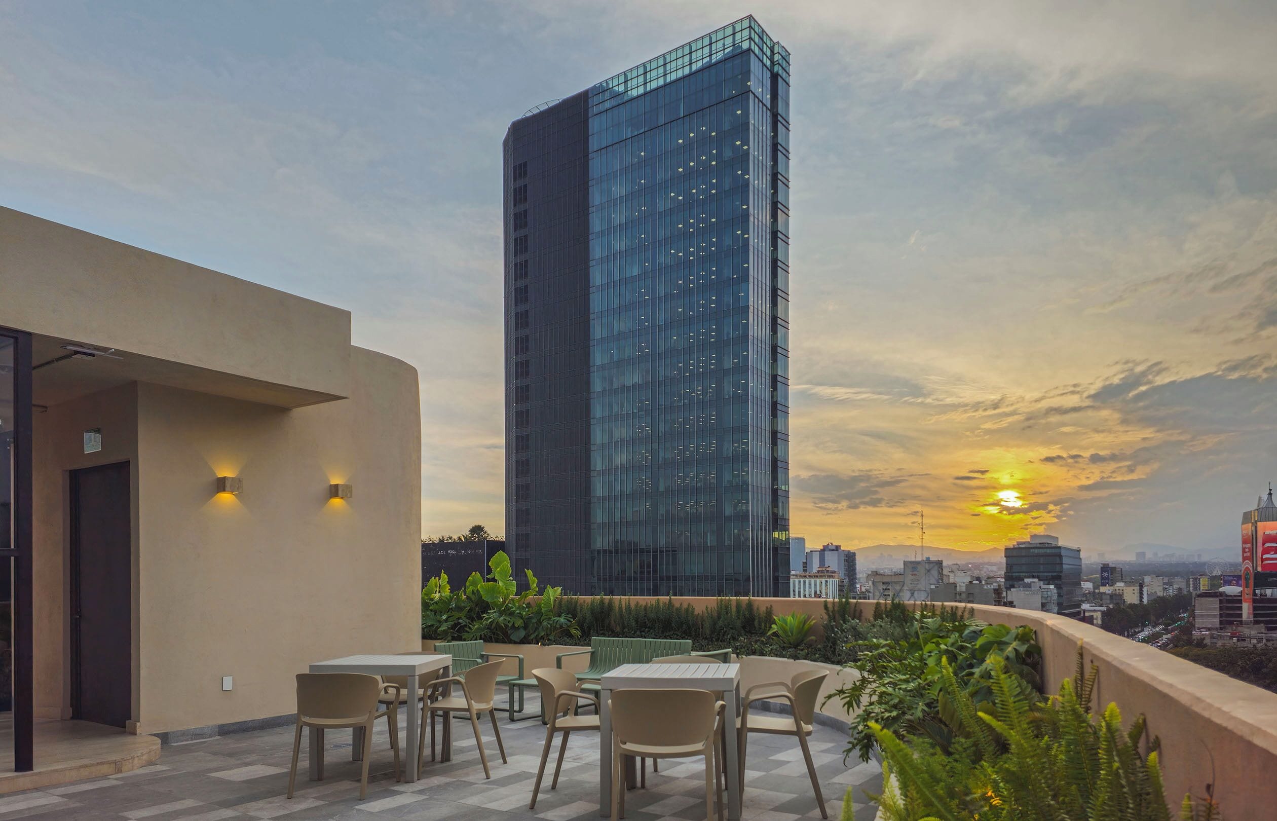Une terrasse sur le toit, dotée d’un espace extérieur aménagé et offrant une vue sur un grand immeuble en verre.