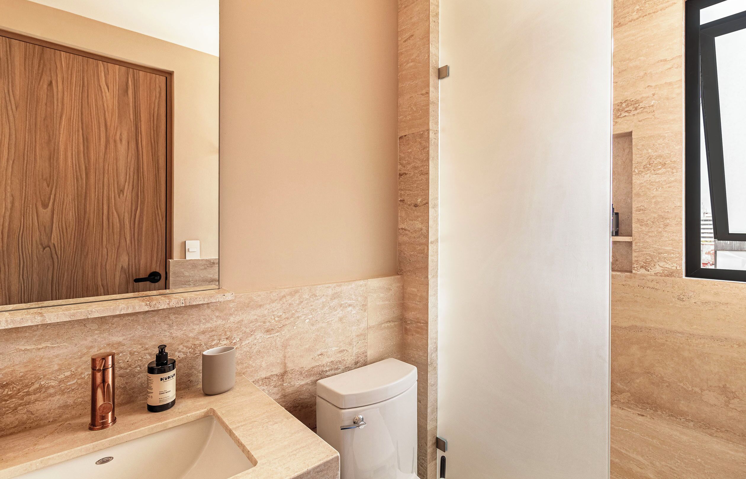A bathroom with a wooden cabinet, a sink, a toilet, and a mirror.