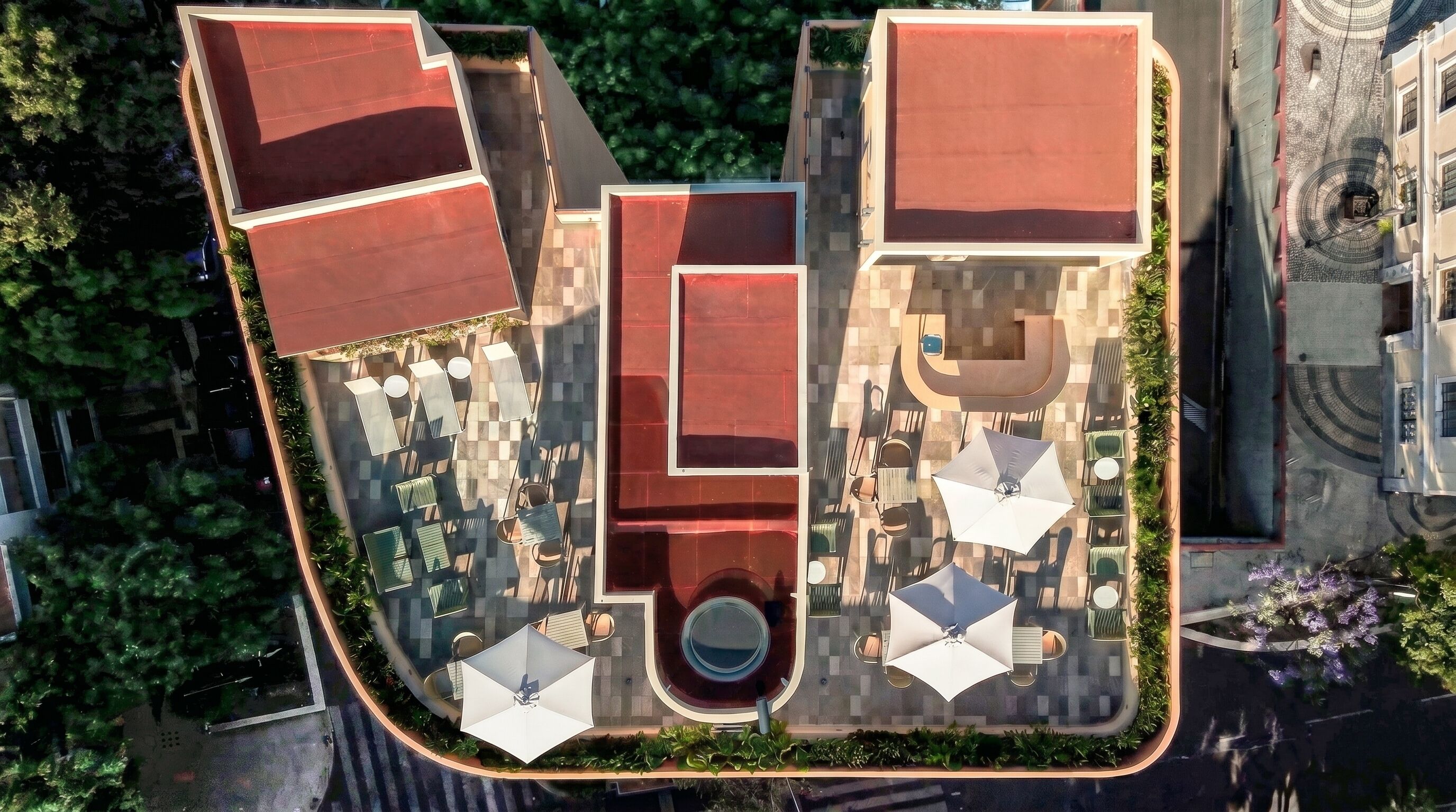 An aerial view of a hotel with a central courtyard, outdoor seating, and a pool.