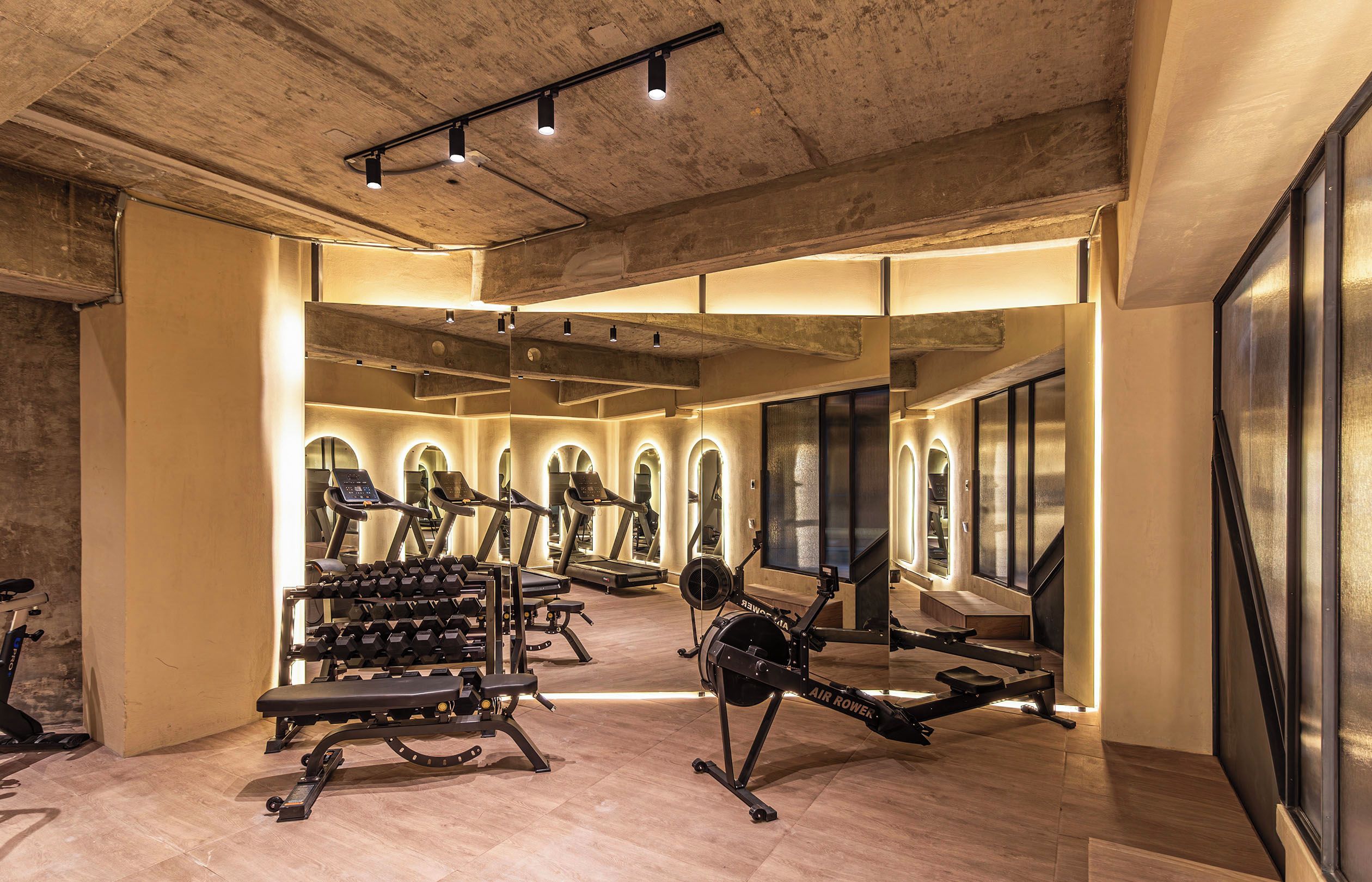 Et fitnesscenter med løbebånd, styrkemaskiner og et spejl.