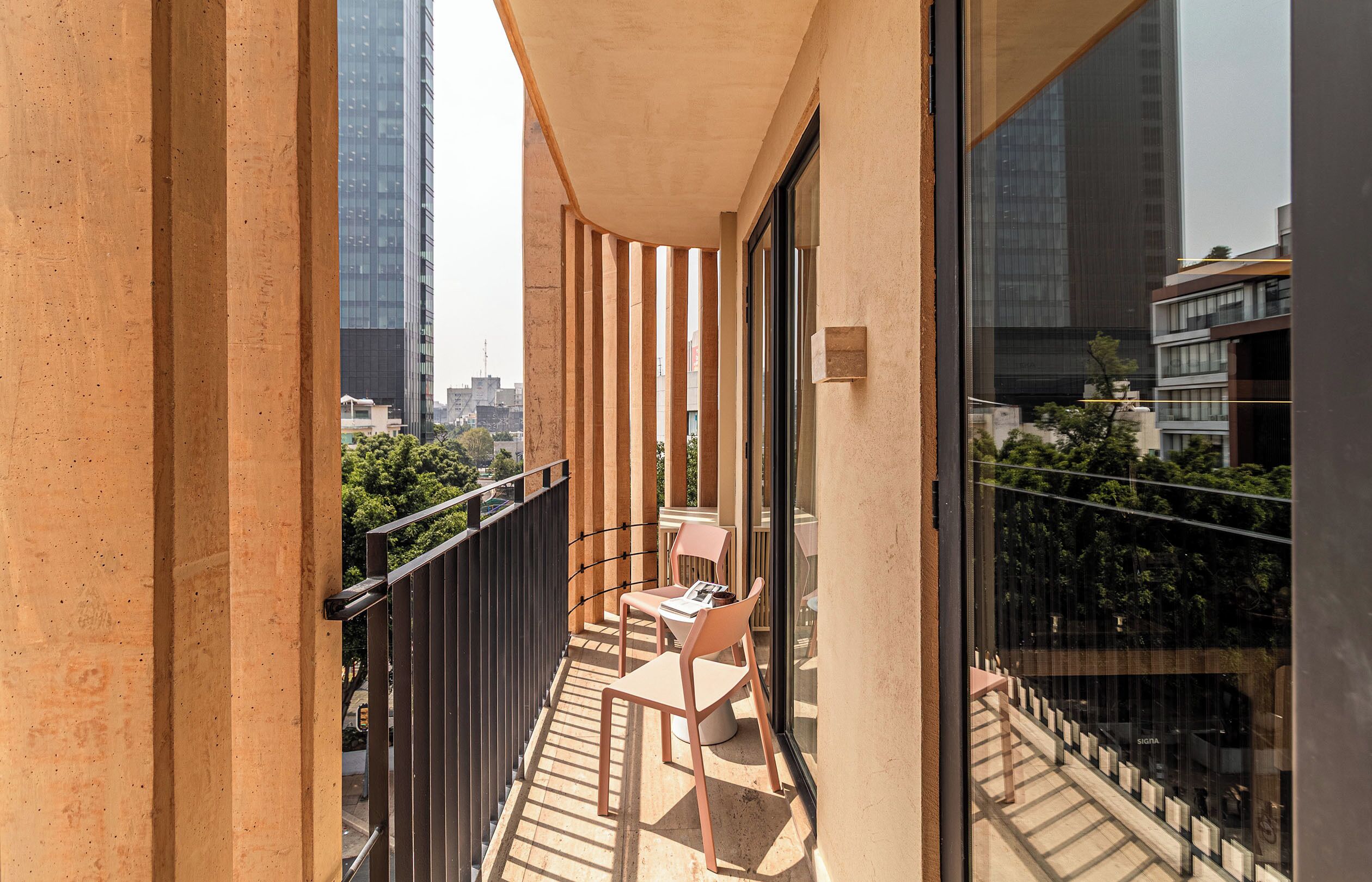 Un balcon donnant sur de grands immeubles, une table et deux chaises.