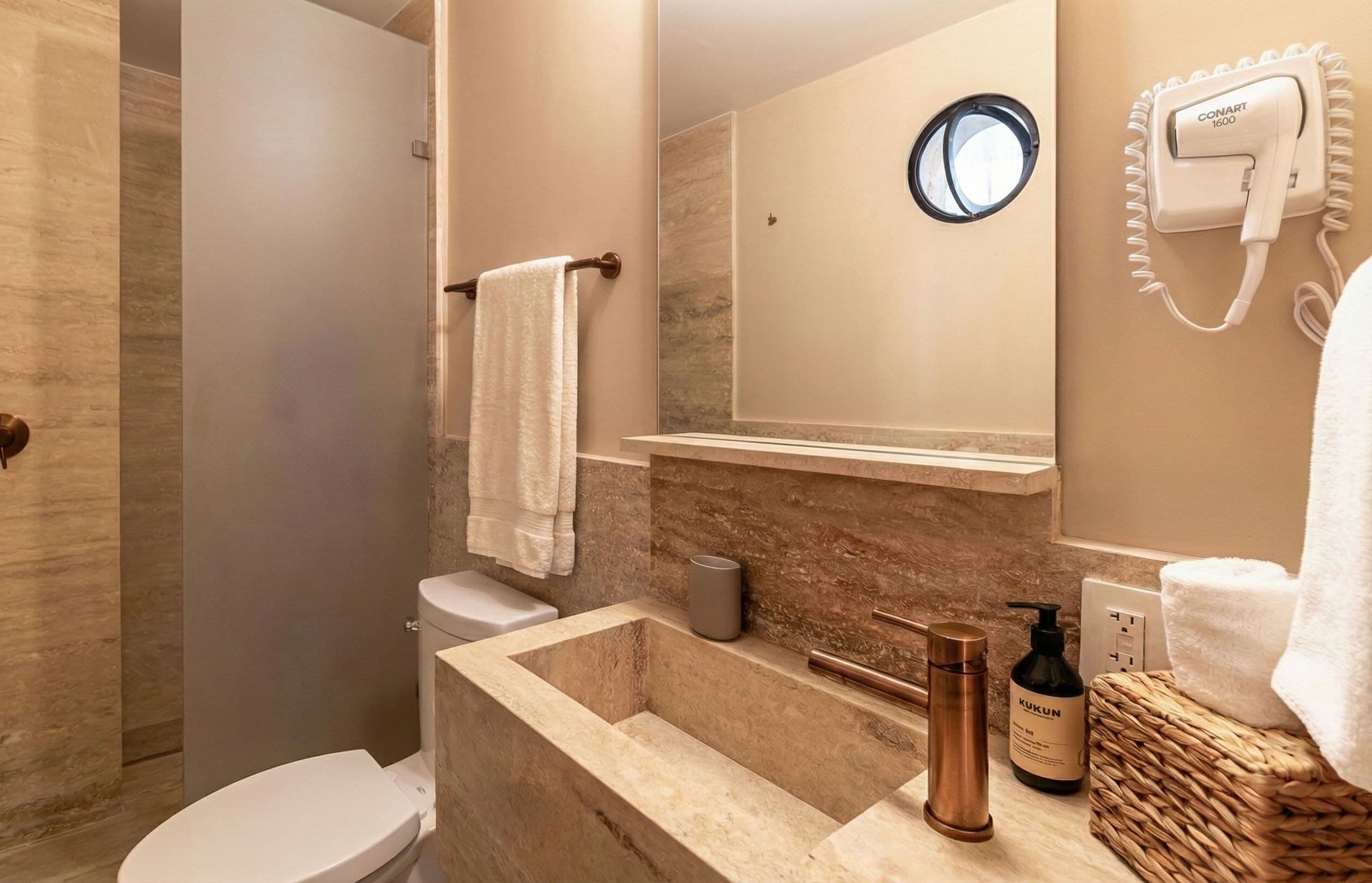 A bathroom with a toilet, sink, mirror, towel rack, and a hairdryer on the wall.
