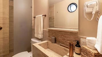 A bathroom with a toilet, sink, mirror, towel rack, and a hairdryer on the wall.