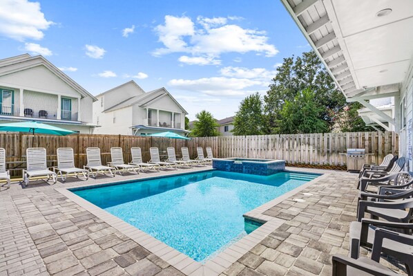 A swimming pool with lounge chairs and a wooden fence.