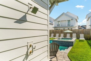 A backyard with a swimming pool, a wooden fence, and a house with a balcony.