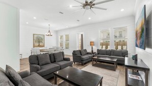 A spacious living room with grey sofas, a coffee table, and a ceiling fan.