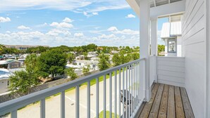 A balcony with a view of a residential area, including houses and a parking lot.
