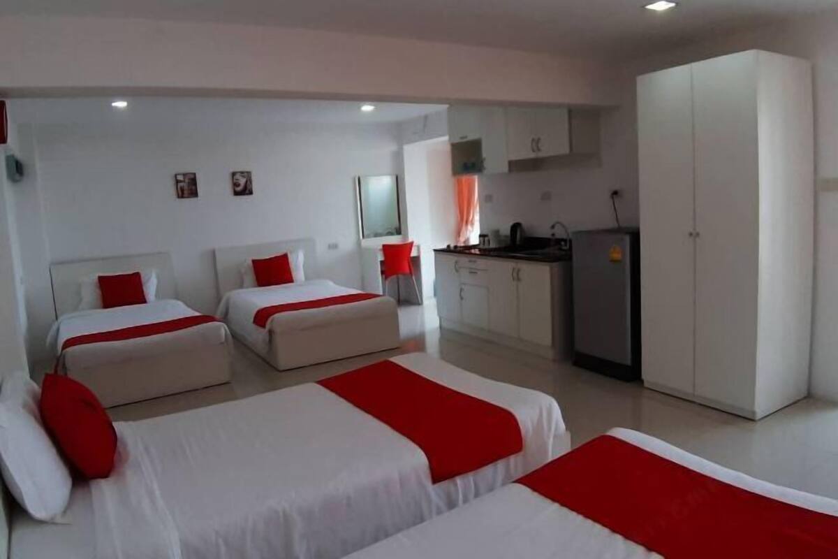 A hotel room with two beds, a kitchenette, and a wardrobe.