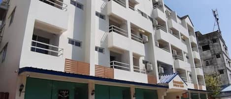 Un edificio de varios pisos con balcones, un toldo verde y un letrero que indica un restaurante.