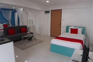 A hotel room with a bed, a sofa, a small table, a desk, and a TV.