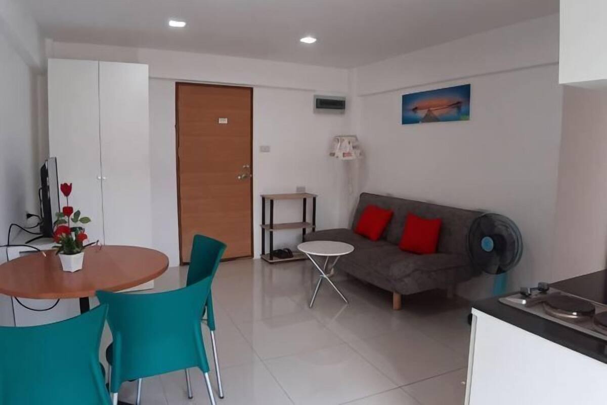 A living area with a sofa, a table with chairs, a door, and a small shelf.