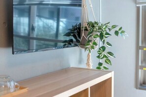 A room with a wooden desk, a hanging plant, and a large window. - Mi-HOTEL OTSUKA (Tokyo)