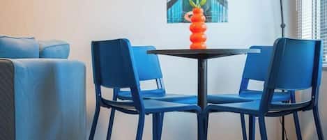 A room with a blue sofa, two blue chairs, a small black table, and a vase with flowers.