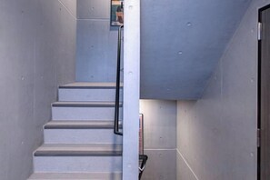 A staircase with a handrail, a door, and a wall with a textured surface. - Mi-HOTEL OTSUKA (Tokyo)