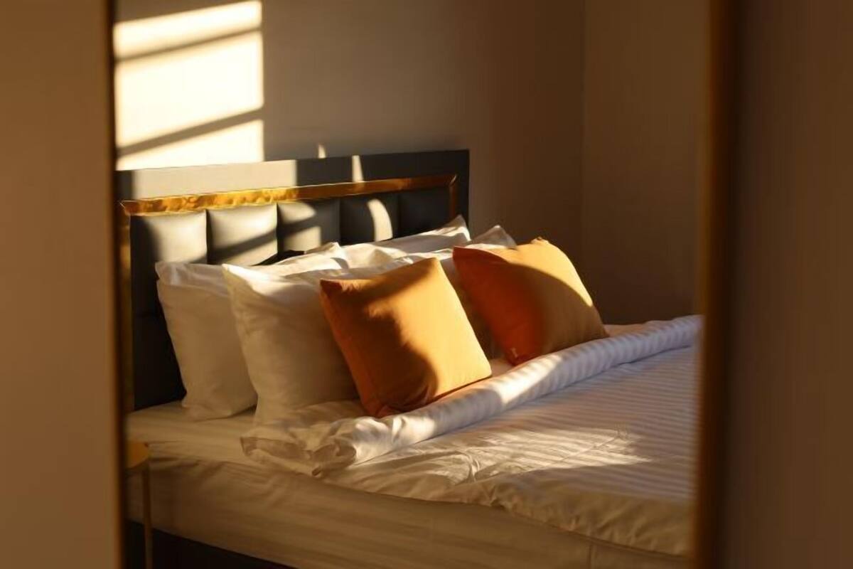 A neatly made bed with a headboard, pillows, and a blanket.