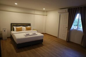 Ein Schlafzimmer mit Bett, Nachttisch, Wandklimaanlage und einem Fenster mit Vorhängen.