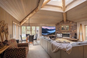 Ein gemütliches Wohnzimmer mit Kamin aus Stein, einem großen Fernseher und einer komfortablen Sitzecke.