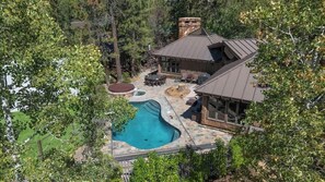 Ein Haus mit Swimmingpool, Sitzgelegenheiten im Freien und einer Steinterrasse.