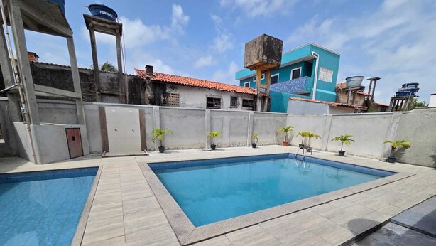 A swimming pool with two separate sections, surrounded by a low wall and potted plants. - Salt Beach Guest House Atalaia (Salinópolis)