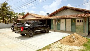 A black pickup truck parked in front of a house with a tiled roof and a garage. - Salt Beach Guest House Atalaia (Salinópolis)