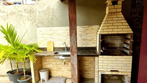 A compact outdoor kitchen with a brick oven, a sink, and potted plants. - Salt Beach Guest House Atalaia (Salinópolis)
