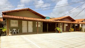 A residential building with a tiled roof, a covered patio area, and a small outdoor seating area with plastic chairs. - Salt Beach Guest House Atalaia (Salinópolis)