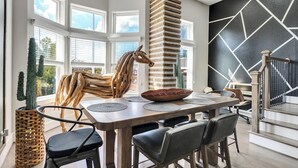 A modern dining area with a wooden table, black chairs, and a unique wooden sculpture centerpiece.