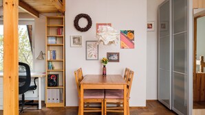 Un comedor con una mesa y sillas de madera, una estantería y adornos en la pared, incluyendo cuadros y una corona.
