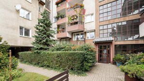 Un edificio residencial de varios pisos con balcones, un patio empedrado y una banca de madera.
