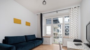 Un salon moderne avec un canapé bleu, une table à manger avec des chaises et de grandes fenêtres avec des rideaux.