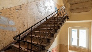 Un escalier orné de rampes en métal travaillées, menant à un palier.