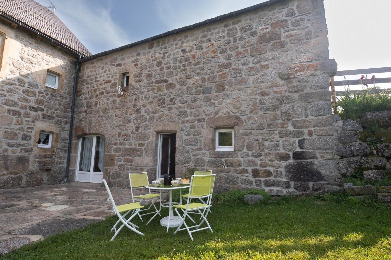 A stone building with a small patio area featuring a round table and four chairs.