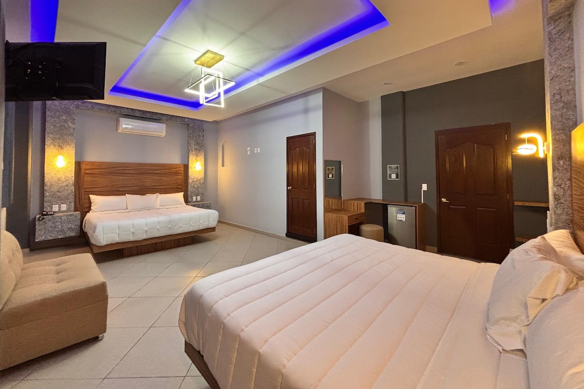 A hotel room with two beds, a TV, a desk, and a mirror.