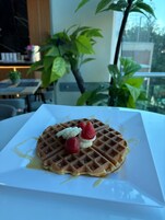 Gofre con fresas y rodajas de plátano sobre un plato blanco, con jarabe por encima.