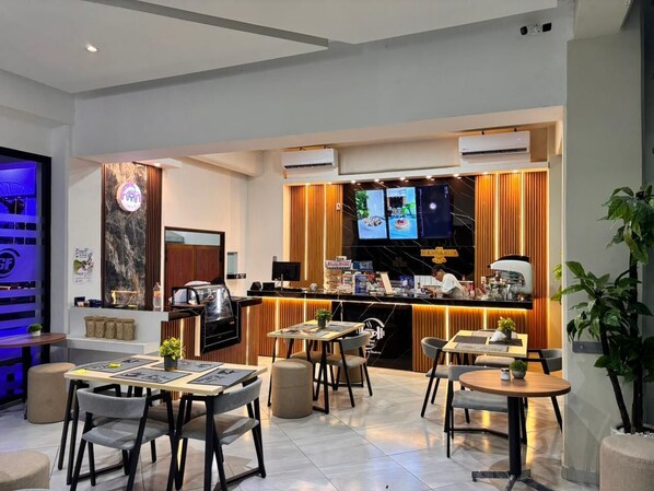 A modern dining area with a bar, seating arrangements, and a television screen. - Grand Hotel Iguala (Iguala de la Independencia)