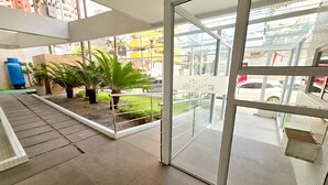 A modern hotel lobby with a glass door leading to a balcony with a view of the street and buildings. - Charming Apartment (Belém)