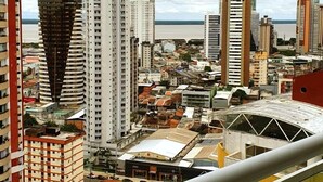 A high-rise building with a unique curved facade, surrounded by other tall buildings and a body of water in the background. - Charming Apartment (Belém)