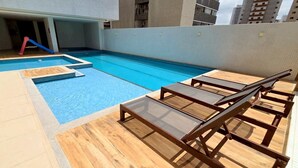 A rooftop pool area with wooden loungers and a small pool. - Charming Apartment (Belém)