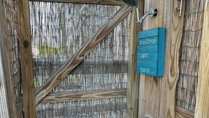Une porte en bois avec une clôture en bambou, une poignée de porte en métal et une pancarte indiquant «Bienvenue».