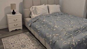 A bedroom with a bed, a nightstand, a ceiling fan, a window with curtains, and a rug. - Emmanuel Midtown 2 BR 1.5 Bath Condo in Tulsa. Close to YMCA, Hospitals, Highway (Tulsa)